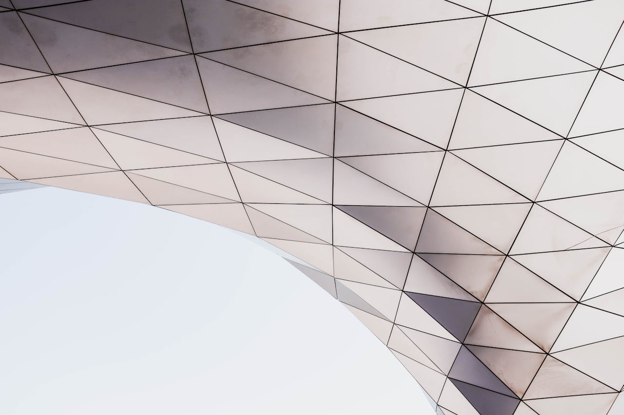 Modern architectural structure with triangular glass panels forming a curved geometric surface