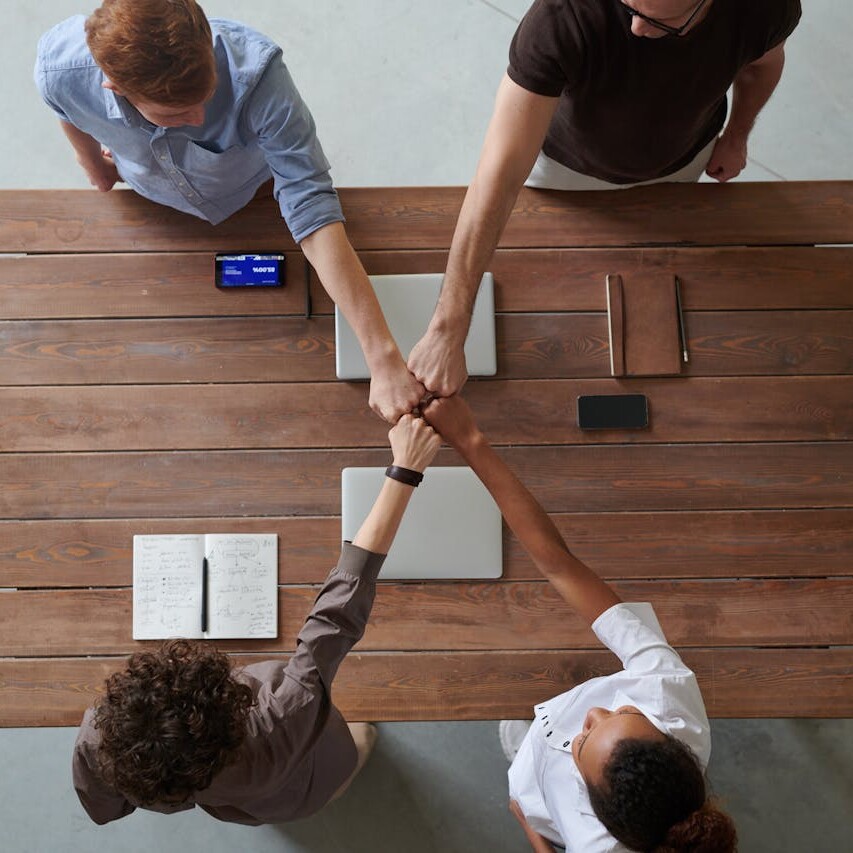 Team of professionals uniting hands over a wooden table, symbolizing trust and collaboration