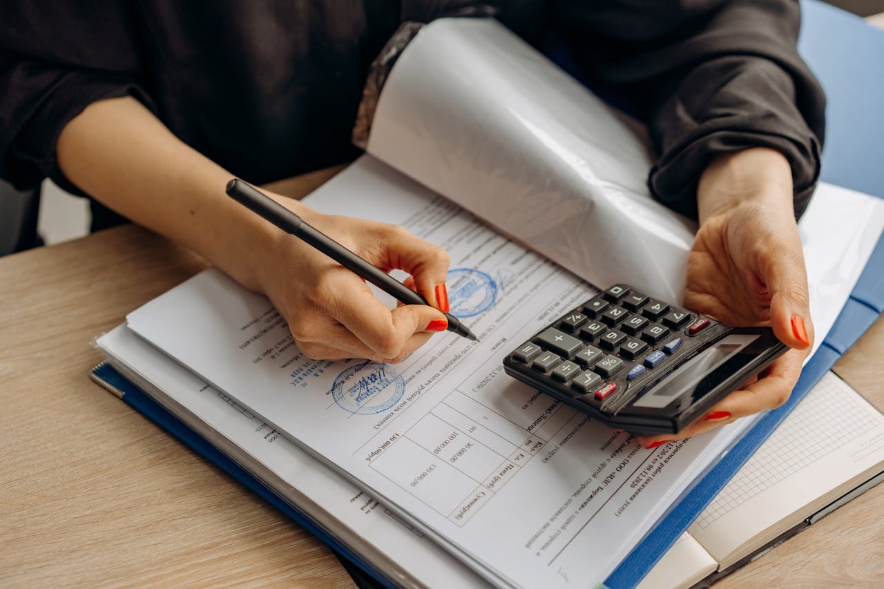 Businesswoman using a calculator and signing financial documents with official stamps