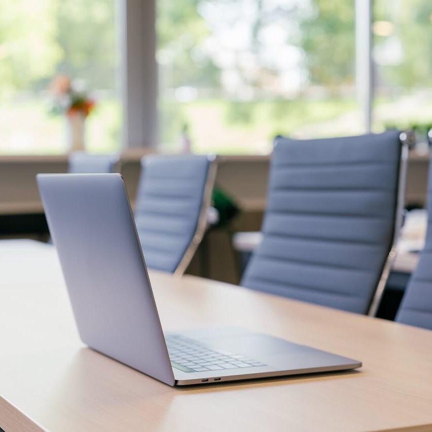 Modern laptop on a boardroom table in a bright office meeting room