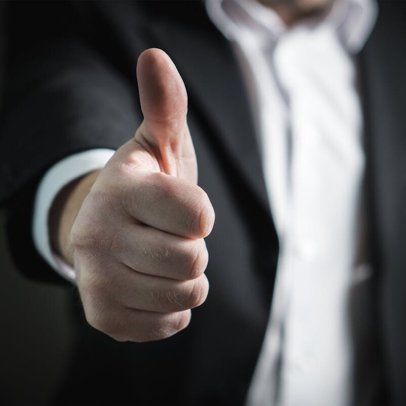 Close-up of a businessman giving a thumbs up gesture, symbolizing approval and confidence