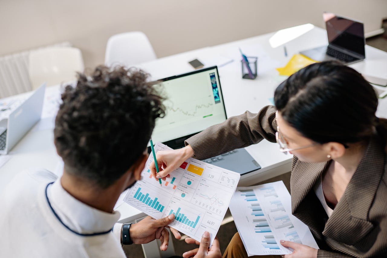 Two colleagues analyzing financial data and charts in front of a laptop during a business meeting