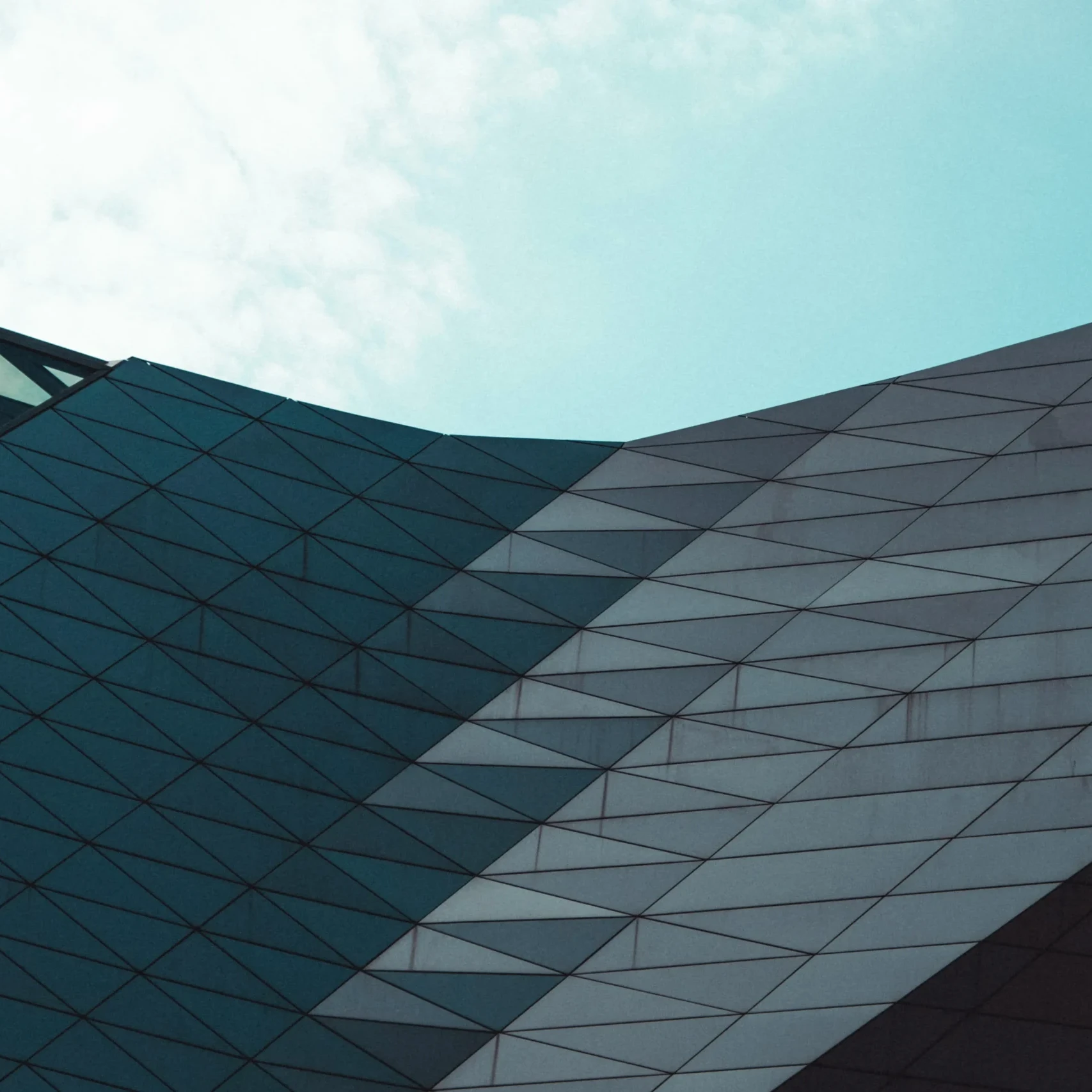 Modern architectural facade with angular geometric panels under a clear sky