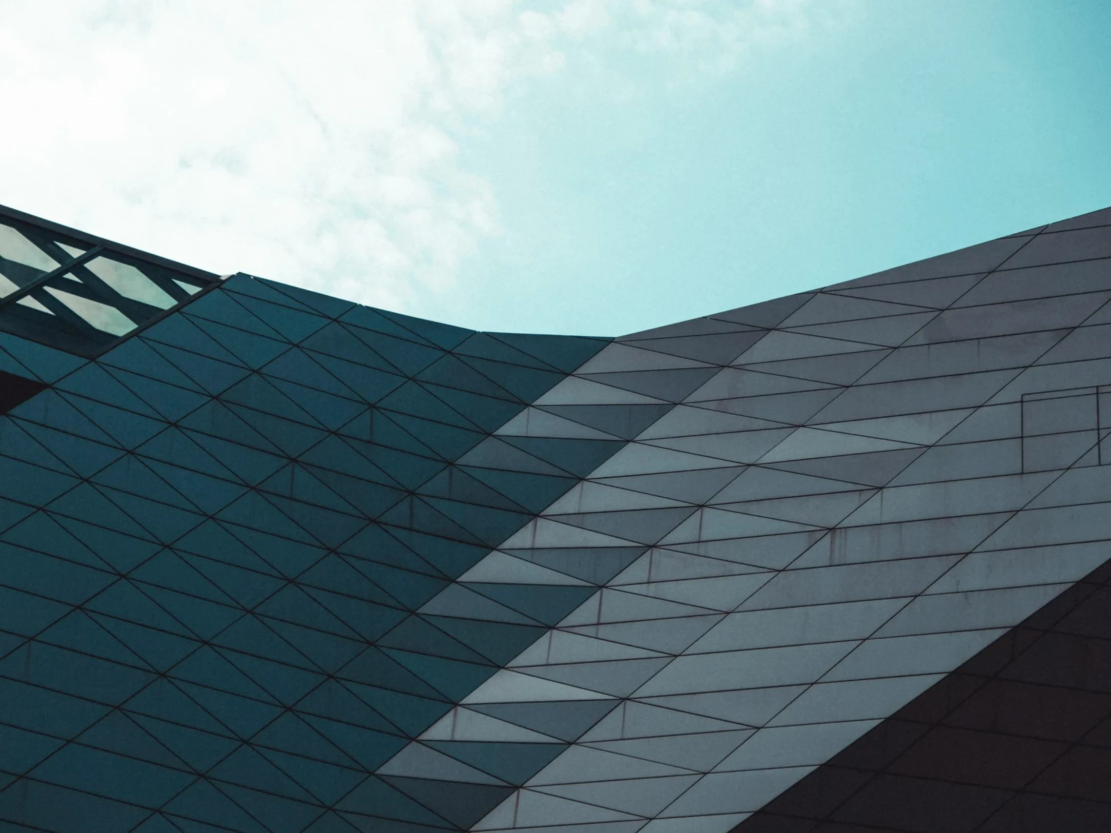 Modern architectural facade with angular geometric panels under a clear sky