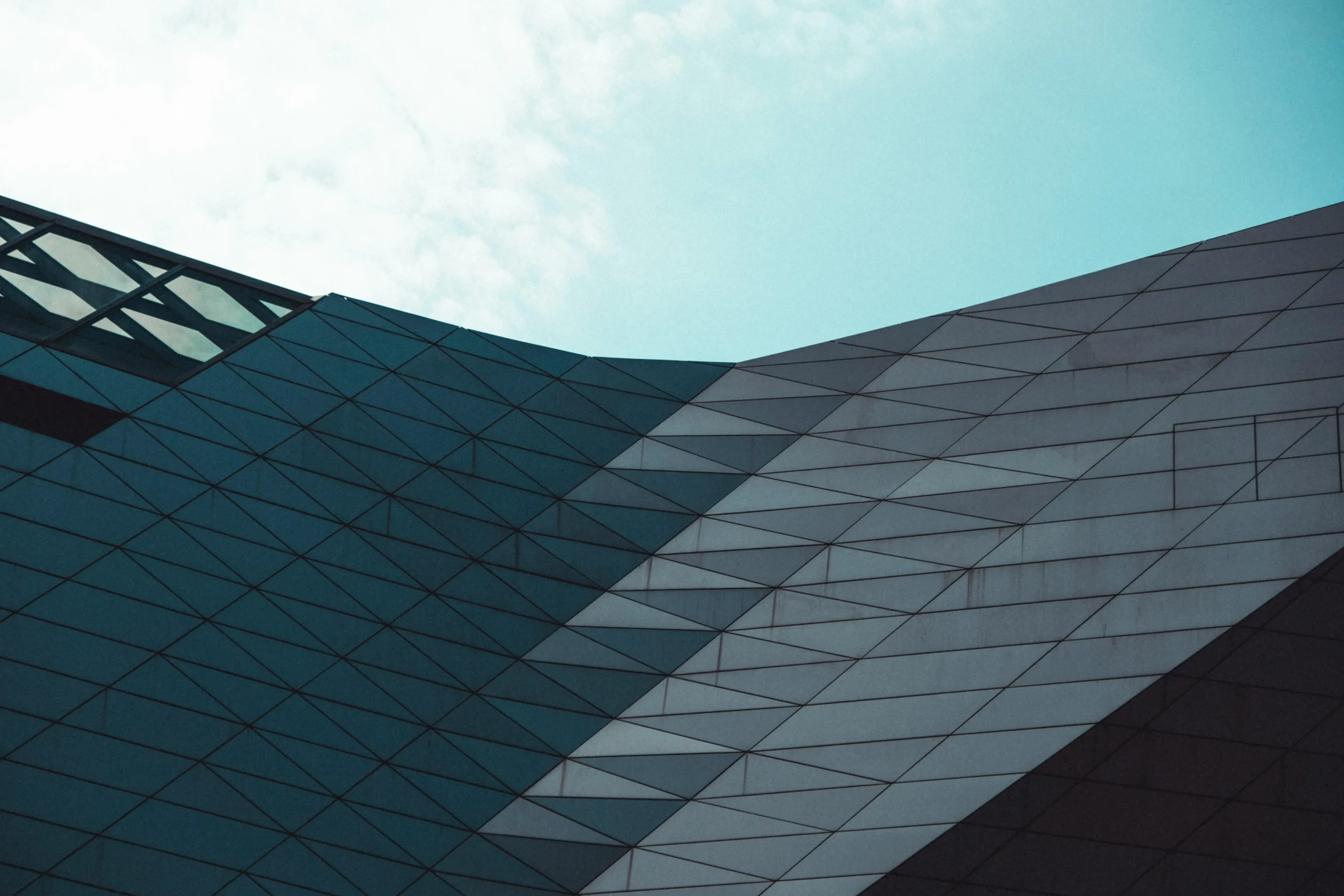 Modern architectural facade with angular geometric panels under a clear sky