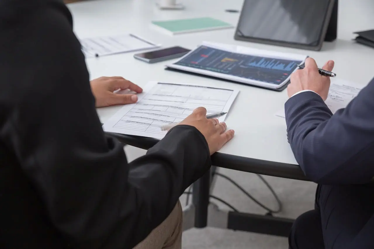 Business professionals reviewing financial documents and analyzing data charts on a digital tablet