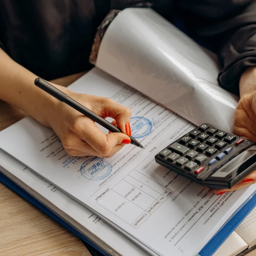 Businesswoman using a calculator and signing financial documents with official stamps