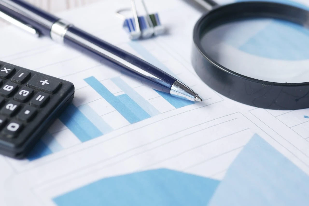 Financial audit tools including calculator, magnifying glass and charts on printed financial reports